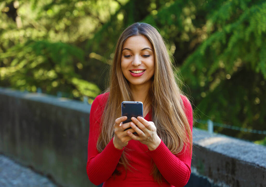 Bella giovane donna che utilizza lo smart phone nel parco
 - Foto, immagini