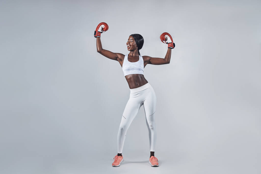 Gyönyörű fiatal afrikai nő boksz kesztyűben tartja a karját - Fotó, kép