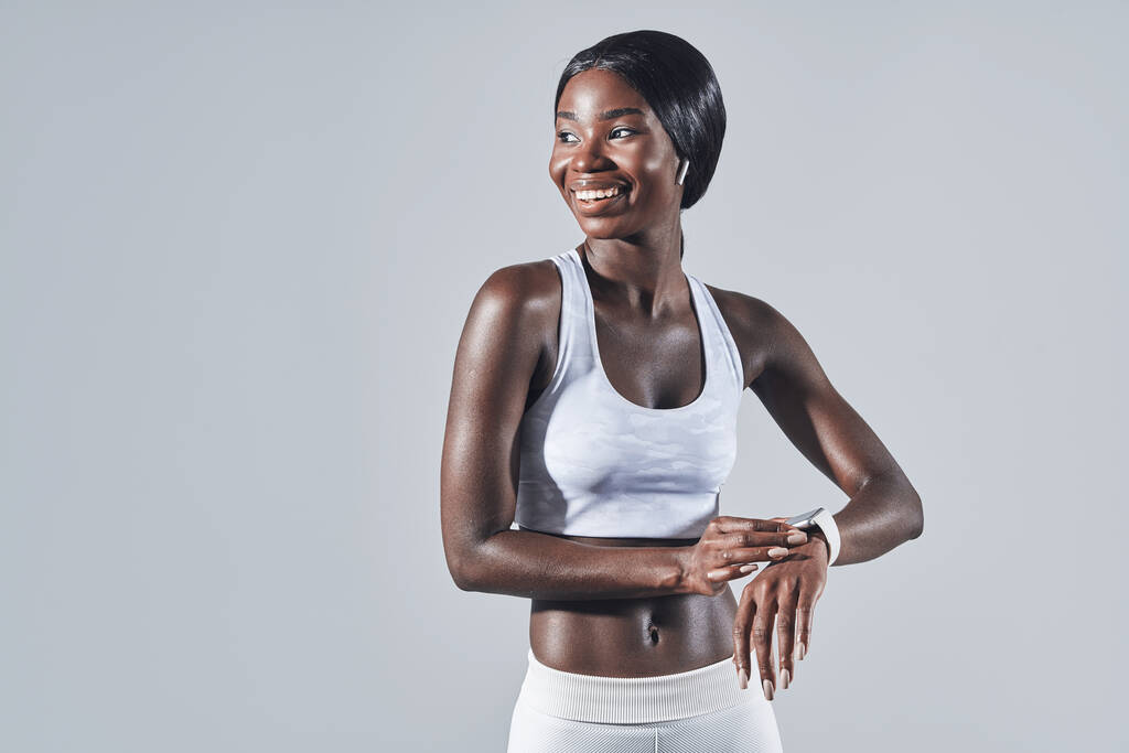 Mujer africana joven y segura en ropa deportiva comprobando el rastreador de fitness - Foto, Imagen