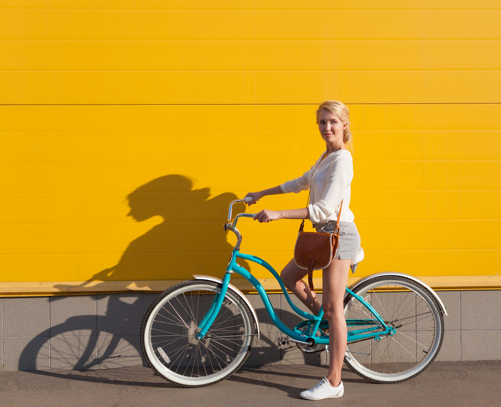 Jeune fille blonde sexy se tient près du vélo vert vintage avec sac vintage brun
 - Photo, image