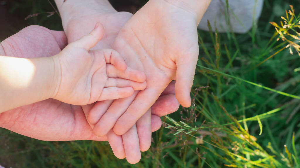 Perheenjäsenet, vanhemmat ja lapset laittavat kätensä toisiinsa rakkauden ja tuen merkkinä.. - Valokuva, kuva