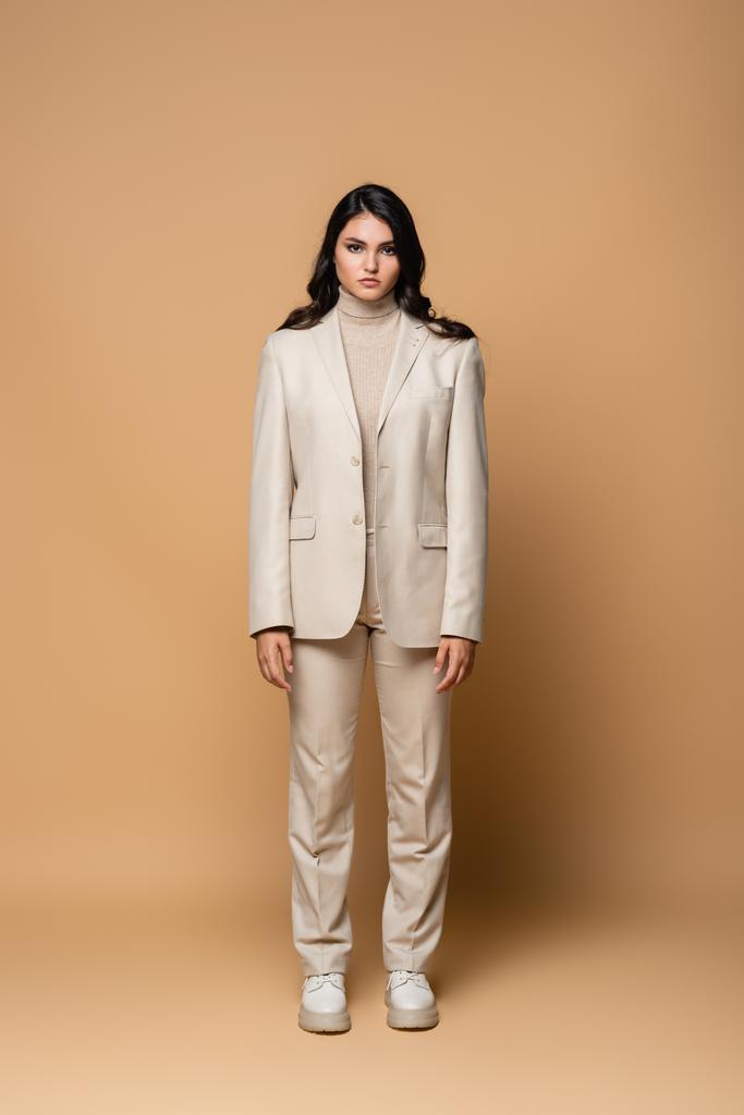 Brünettes Modell im trendigen Anzug auf beige  - Foto, Bild