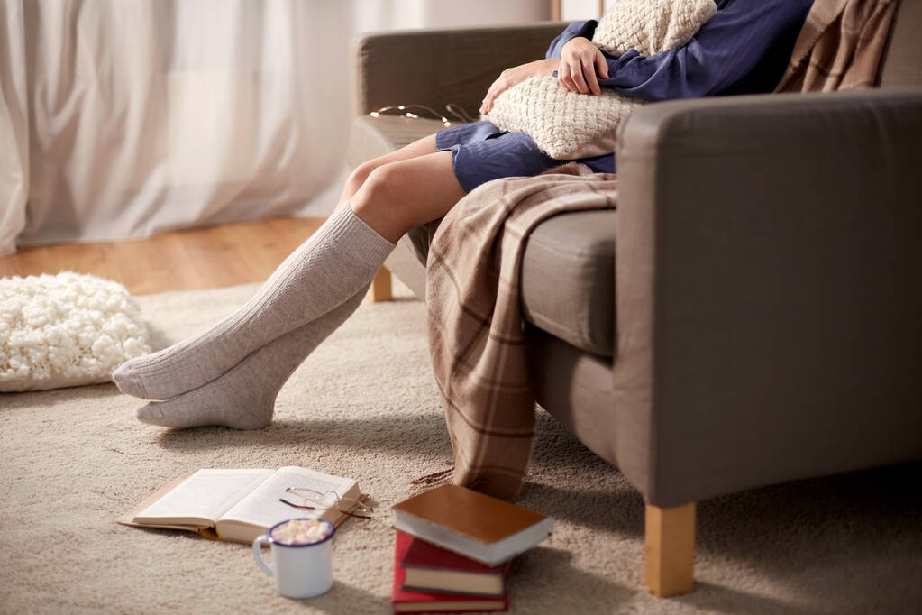Frau in Socken mit Kissen und Büchern zu Hause - Foto, Bild