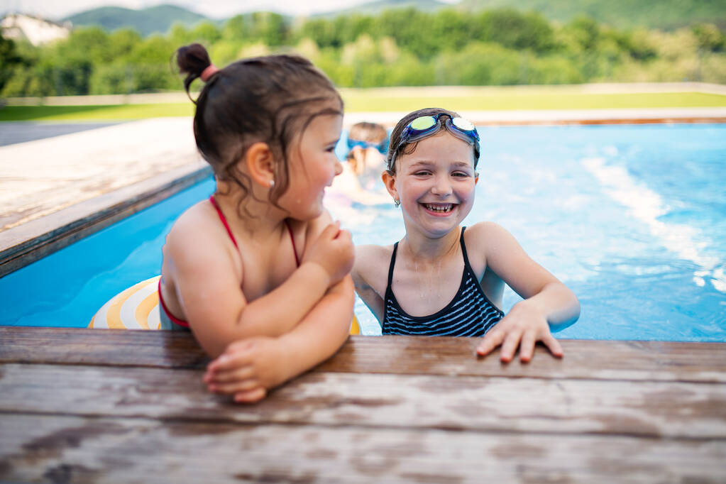 Dwie małe dziewczynki siostry na podwórku, rozmawiające w basenie. - Zdjęcie, obraz