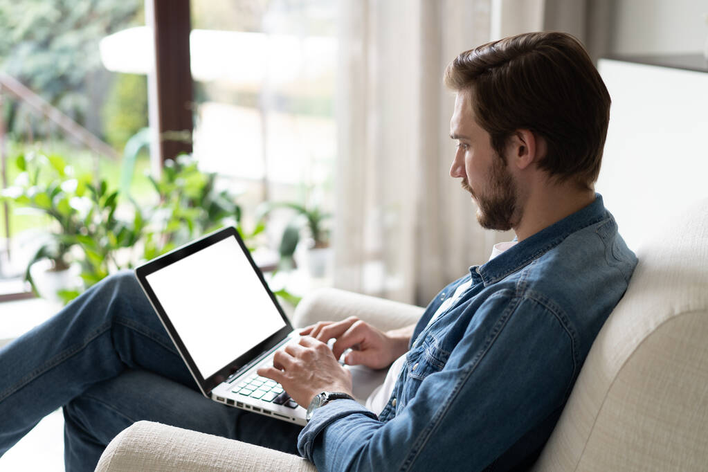 Jeune homme travaillant sur son ordinateur portable avec écran d'espace de copie vierge pour votre message texte publicitaire dans le bureau à la maison - Photo, image