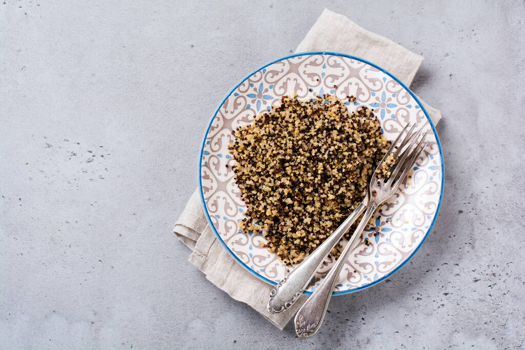 Gekochte weiße, rote und schwarze Quinoa in weißem Teller auf grauem rustikalem Hintergrund, Ansicht von oben, Platz für Textrezepte oder Speisekarte. Veganes Superfood, gesunde Ernährung oder Ernährungskonzept. - Foto, Bild