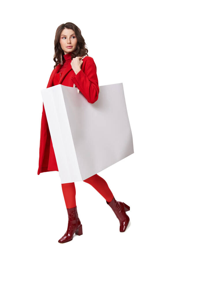 Stüdyoda elinde alışveriş çantasıyla duran kırmızı ceketli kadın. - Fotoğraf, Görsel