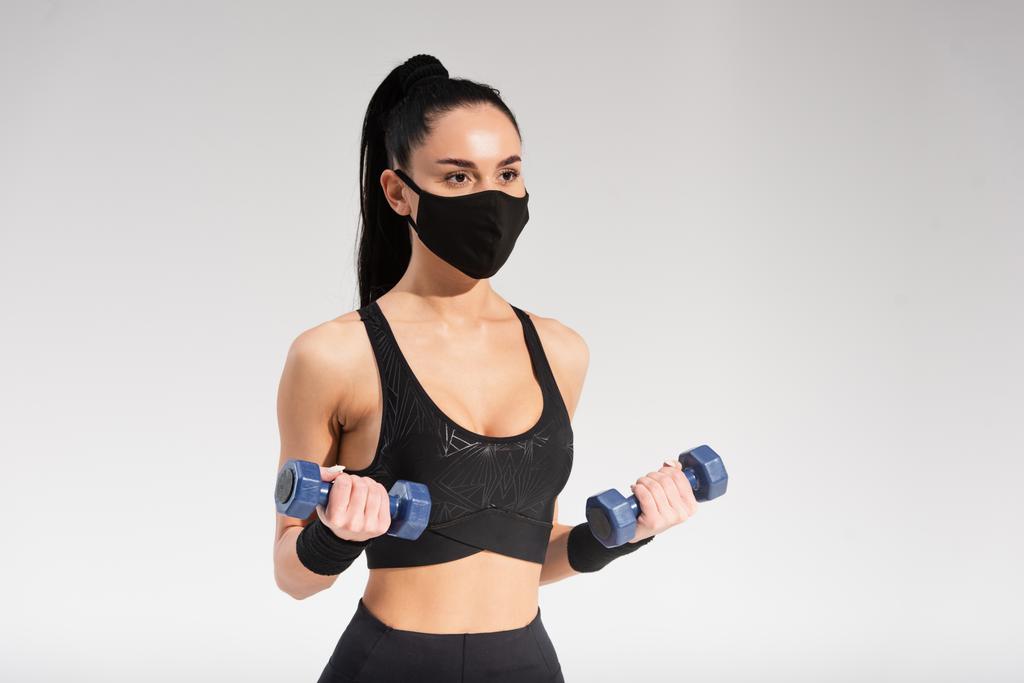 sportovkyně v černé ochranné masce cvičení s činkami na šedé - Fotografie, Obrázek