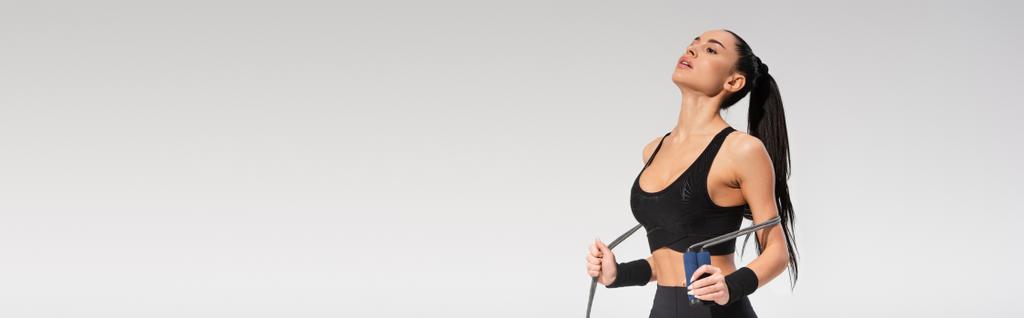 jong sportief vrouw houden springtouw op grijs, banner - Foto, afbeelding