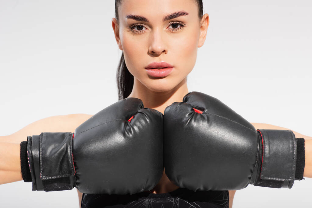 brunetka mladá sportovkyně v boxerských rukavicích izolovaných na šedé - Fotografie, Obrázek