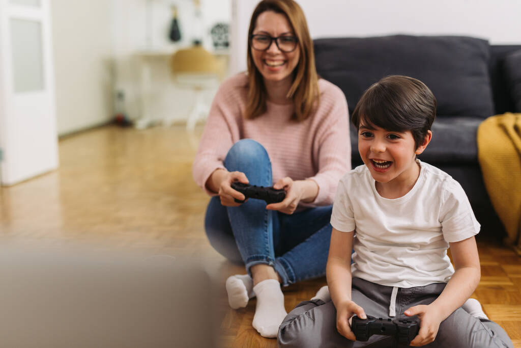mère et enfant jouer à des jeux vidéo à la maison - Photo, image