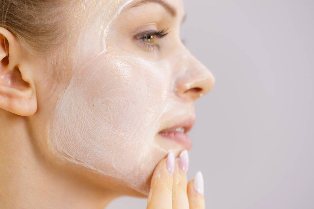 Молодая женщина наносит крем косметический, маска увлажняет ее лицо. Косметика. Skincare. - Фото, изображение