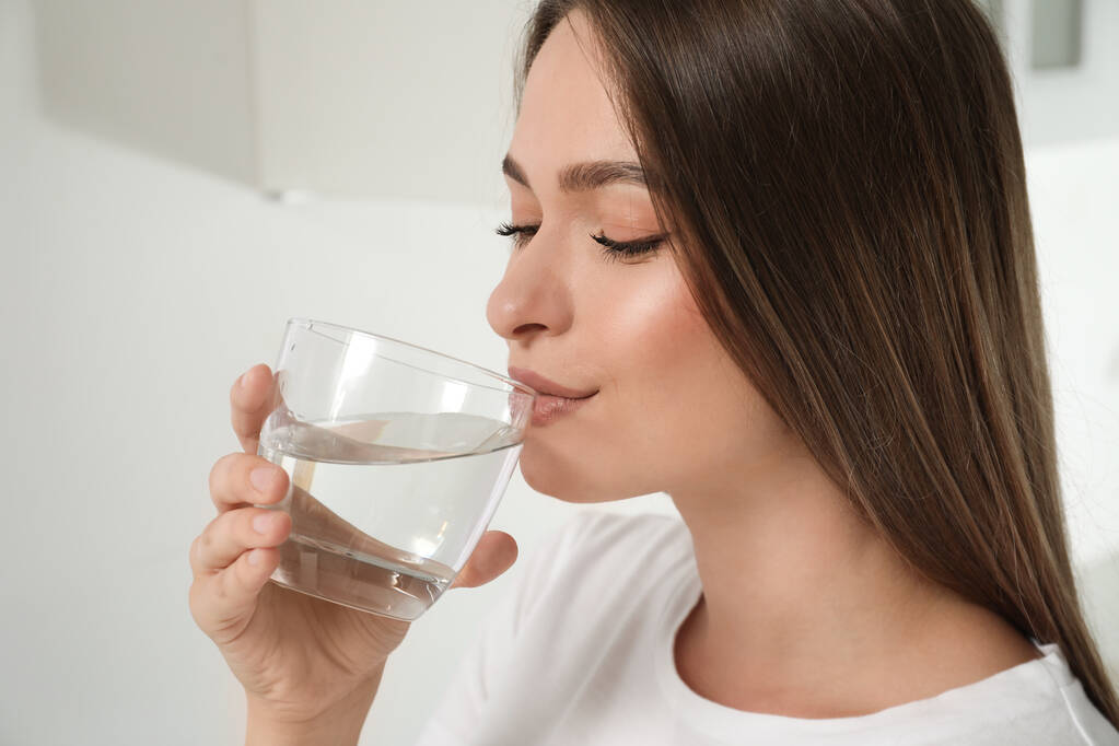 Mujer bebiendo agua del grifo de vidrio en casa, primer plano - Foto, imagen