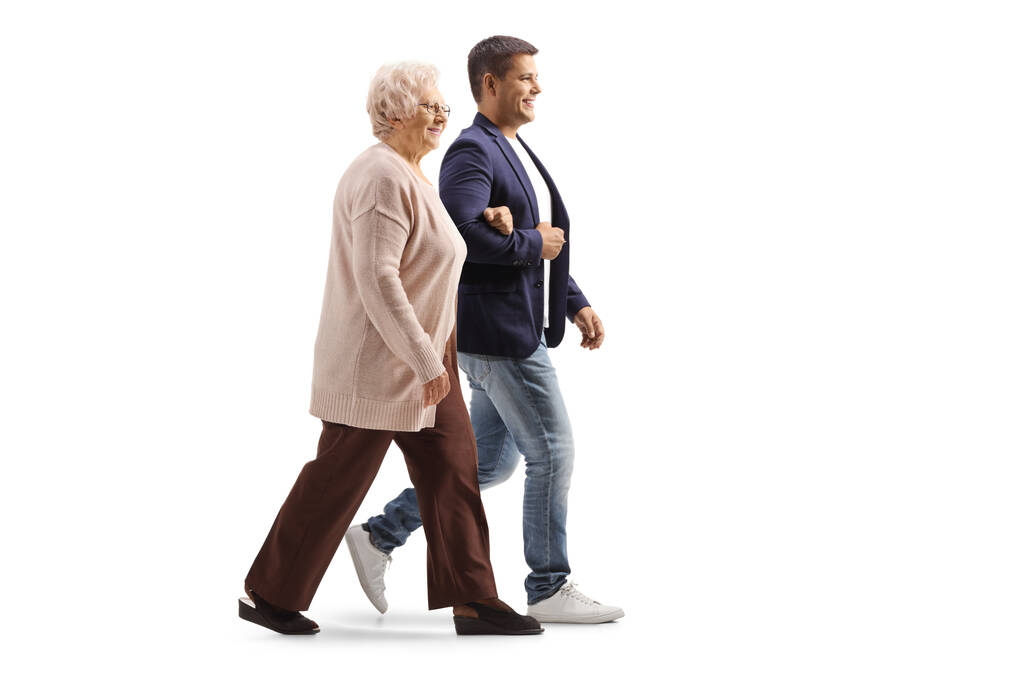 Täyspitkä profiilikuva nuoresta miehestä kävelemässä iäkkään naisen kanssa valkoisella pohjalla - Valokuva, kuva