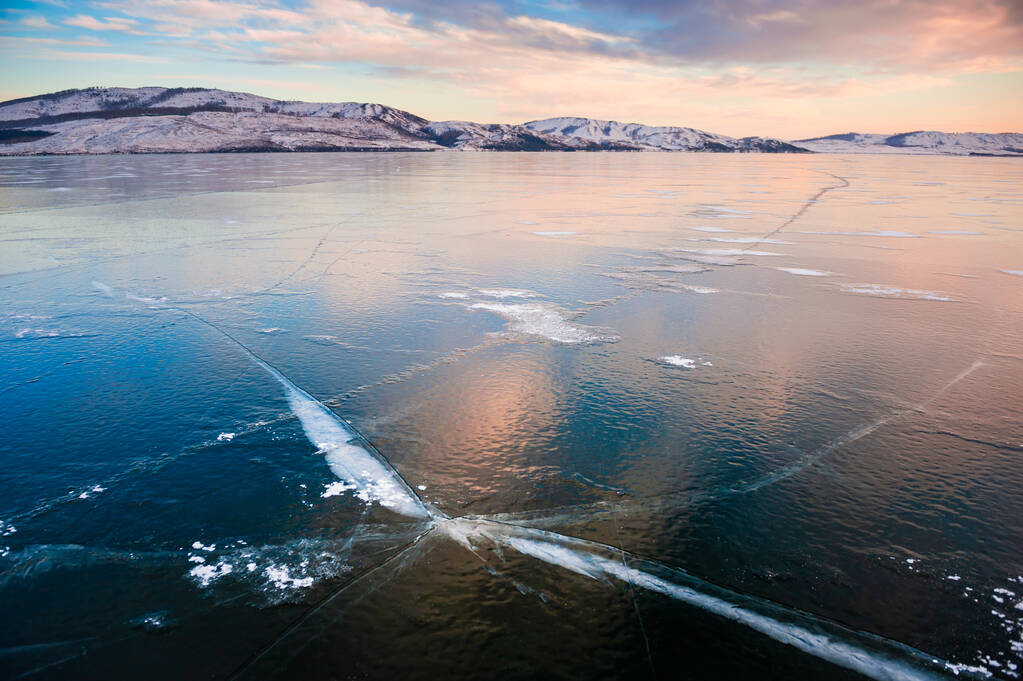 Hielo en el lago congelado al atardecer. Montañas y nubes se reflejan en la superficie de hielo del lago. Hermoso paisaje de invierno. Ural Sur, Rusia - Foto, Imagen