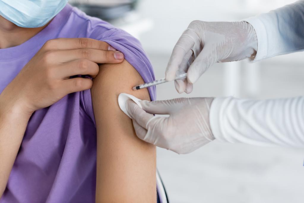 частковий вид медсестри в латексних рукавичках, що дають ін'єкції вакцини людині
 - Фото, зображення