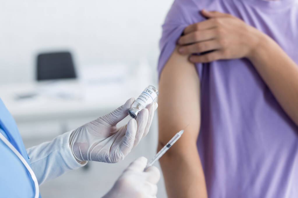 医師が瓶や注射器を持ち患者の近くにワクチンを注射するという - 写真・画像