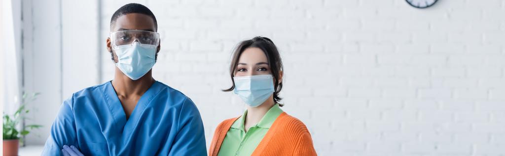 young woman and african american physician in medical masks looking at camera, vaccination concept, banner - Photo, Image
