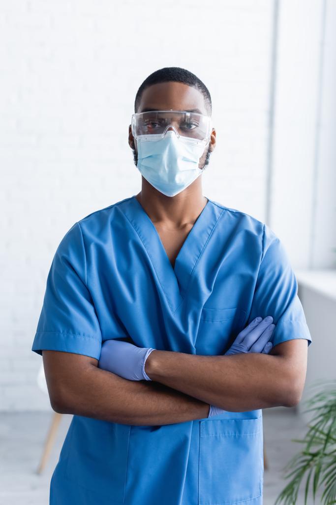 Afrikkalainen amerikkalainen mies univormu ja lääketieteellinen naamio seisoo ristissä kädet, rokotus käsite - Valokuva, kuva