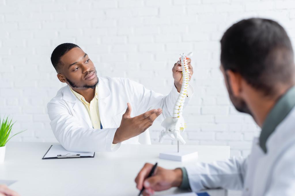 african american physician pointing at spine model near blurred colleague - Photo, Image