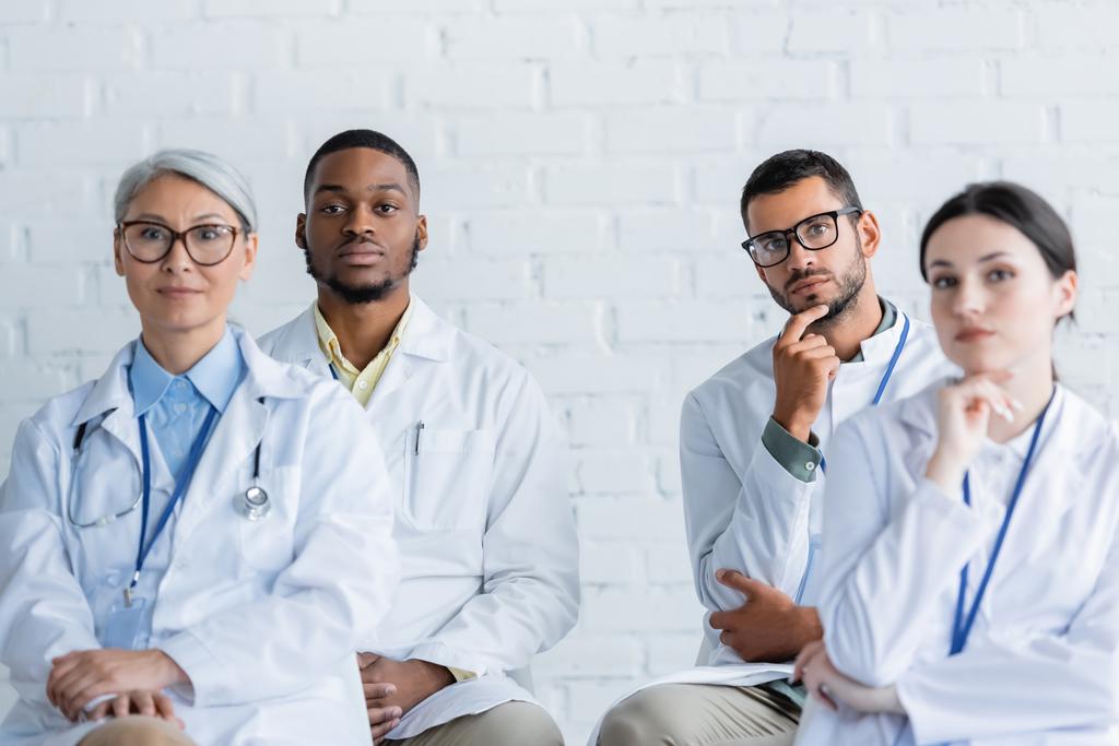 soustředění multietničtí lékaři v bílých pláštích sedící během konference - Fotografie, Obrázek