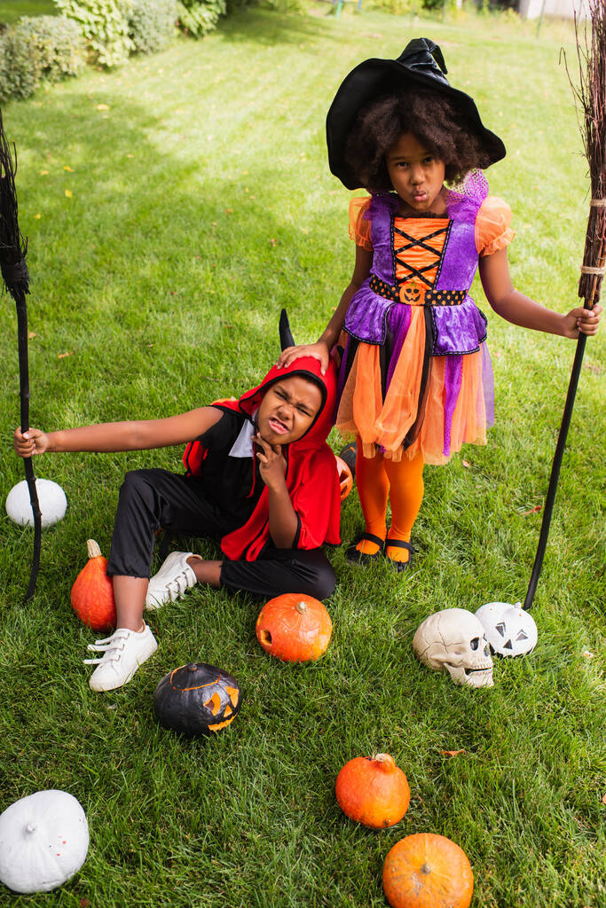 vista de ángulo alto de los niños afroamericanos en disfraces de Halloween con escobas afuera  - Foto, imagen