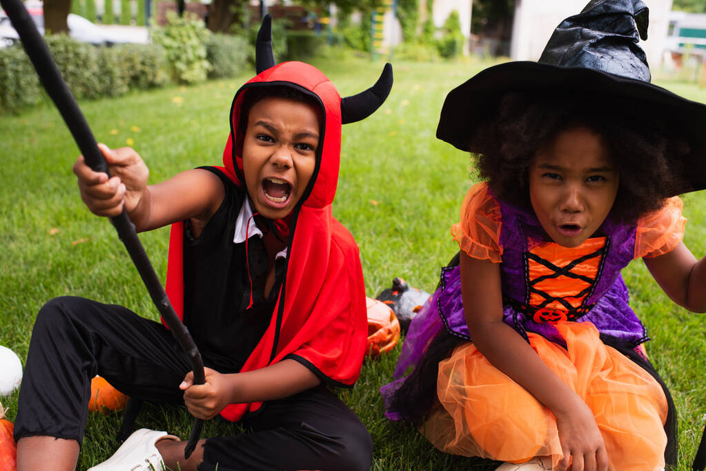 Afričtí američtí sourozenci v halloween kostýmy křičí při hraní na dvorku - Fotografie, Obrázek