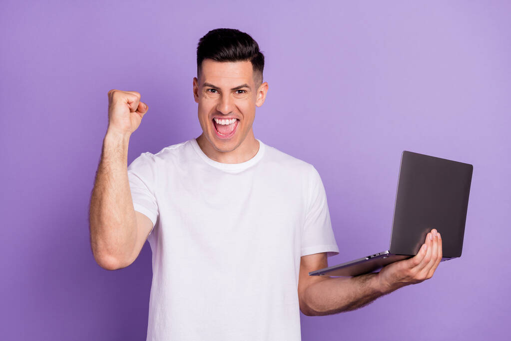 若い男の写真幸せな正笑顔ホールドノートパソコン祝い勝利興奮絶縁上の紫色の背景 - 写真・画像