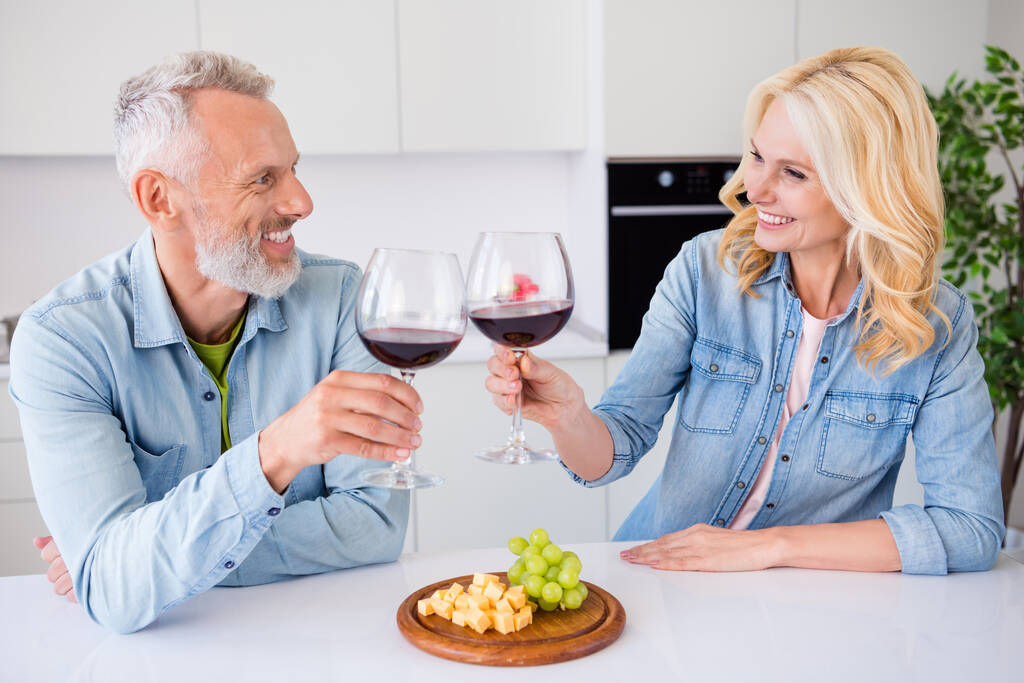 Foto van lachende vrolijke mooie paar vrouw en man drinken wijn clink toast eten voorgerecht vieren home date - Foto, afbeelding