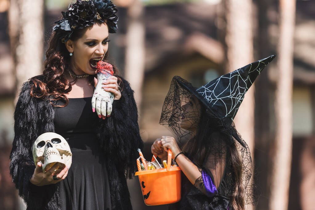 woman in vampire halloween costume scaring daughter with toy hand - Photo, Image