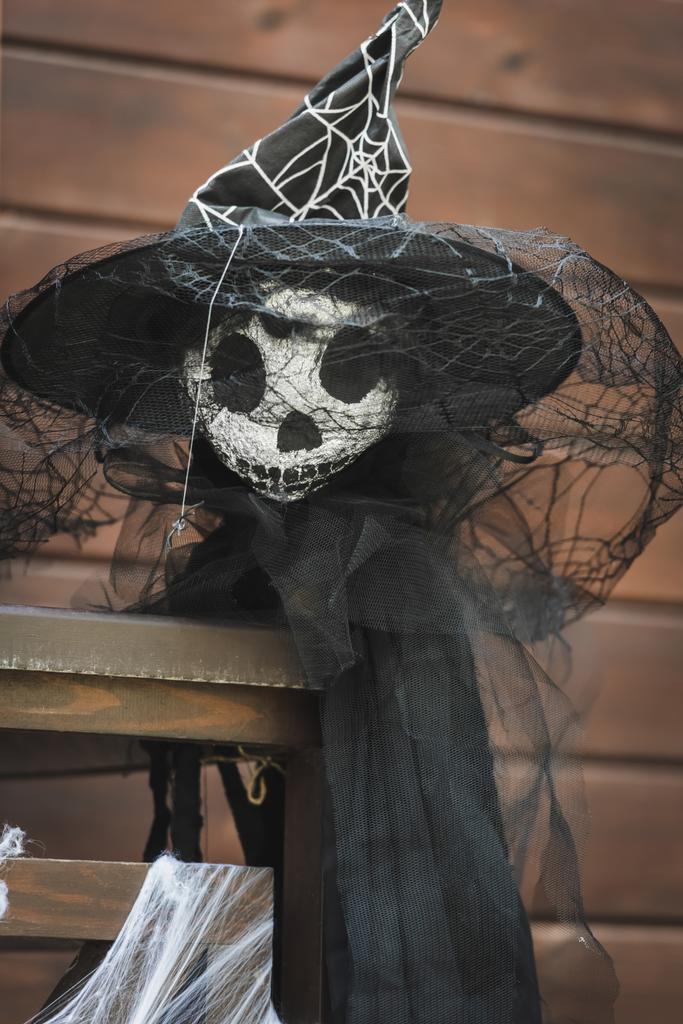 Kara peçeli cadı şapkalı korkuluk ahşap kulübenin çitinde - Fotoğraf, Görsel