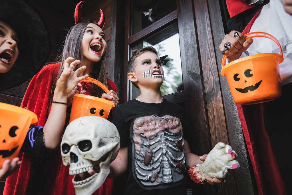 дикі діти в костюмах Хеллоуїна кричать і ростуть на людині з відром
 - Фото, зображення