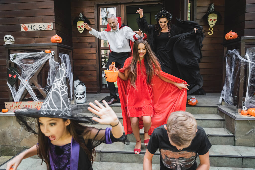 crianças emocionadas com atributos halloween gritando enquanto correndo para fora dos vizinhos - Foto, Imagem