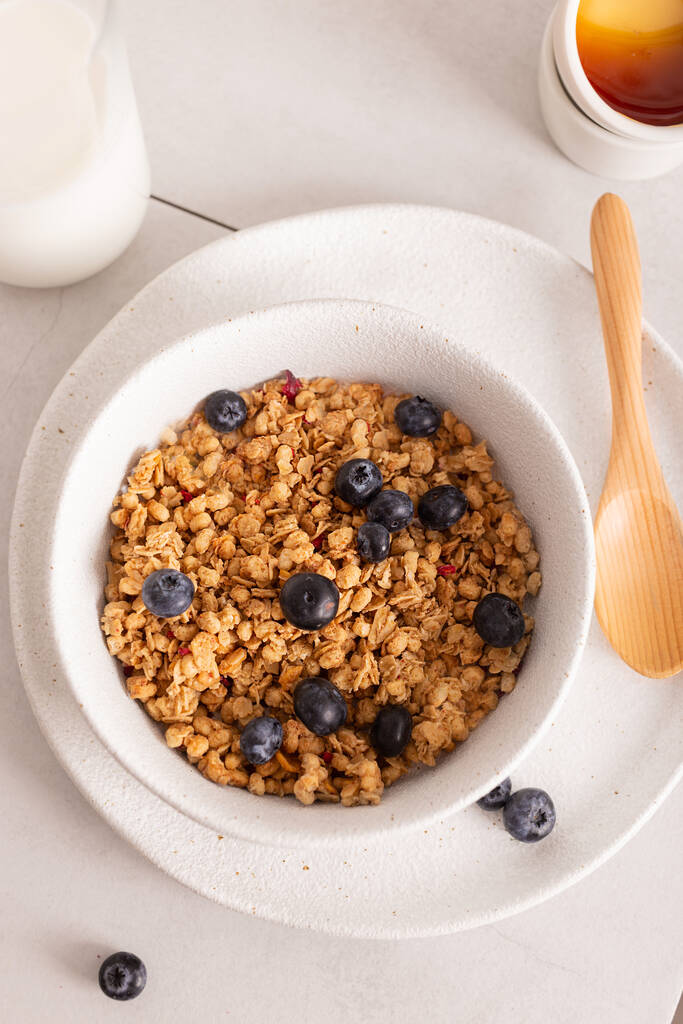 Gezond ontbijt met knapperige granola met bosbessen in een witte kom - Foto, afbeelding