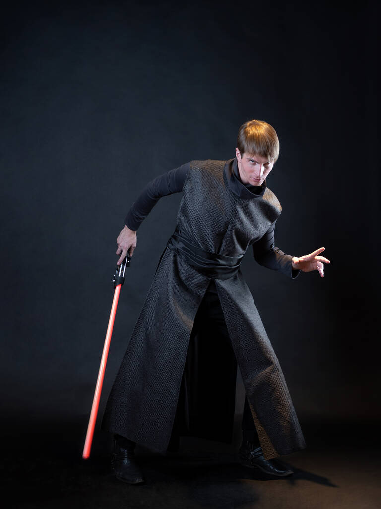 Un méchant avec un sabre laser rouge, un jeune homme en robe longue pose les combats, - Photo, image