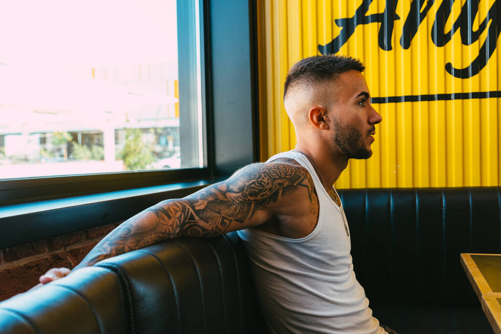 Egy jóképű tetovált férfi ül a kávézóban. - Fotó, kép