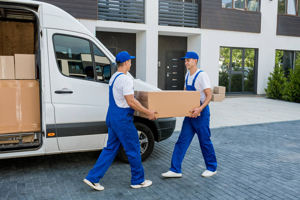 Два працівники компаній з вивезення розвантажують коробки з мікроавтобуса в новий будинок
 - Фото, зображення