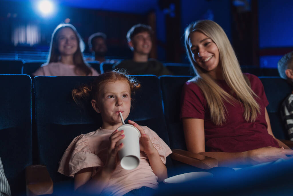 Mère avec de jeunes enfants heureux au cinéma, regarder un film et boire avec une paille. - Photo, image