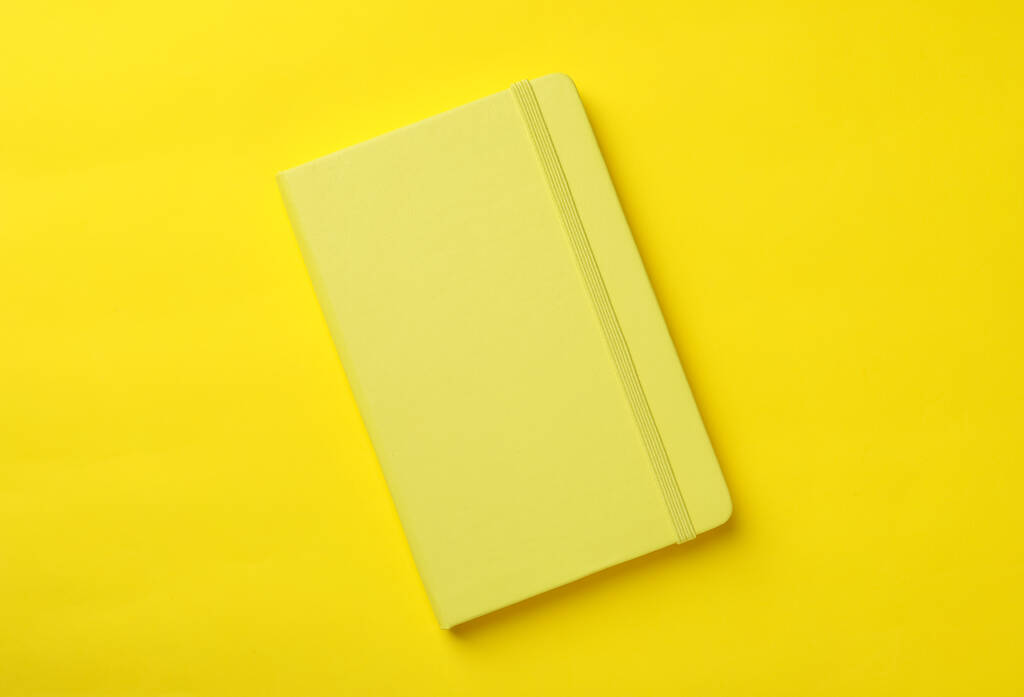Novo planejador elegante com capa dura no fundo amarelo, vista superior - Foto, Imagem