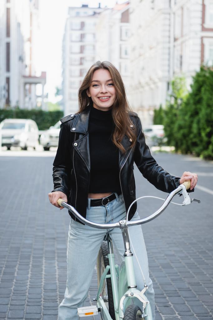 happy young woman riding bicycle on urban street of europe  - Photo, Image