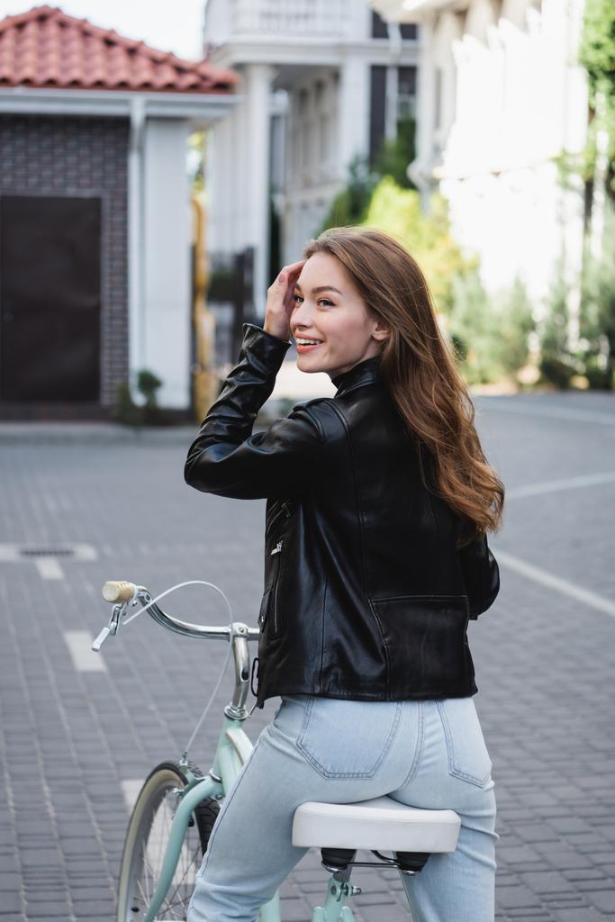 pleased young woman riding bicycle on urban street of europe  - Photo, Image