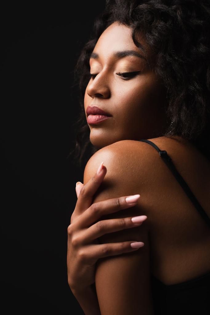 encaracolado afro-americano mulher tocando ombro isolado no preto - Foto, Imagem