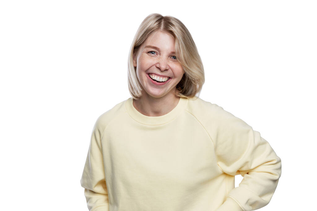 Jovencita riéndose. Bonita rubia con un suéter amarillo. Felicidad, positividad y libertad. Aislado sobre fondo blanco. - Foto, Imagen