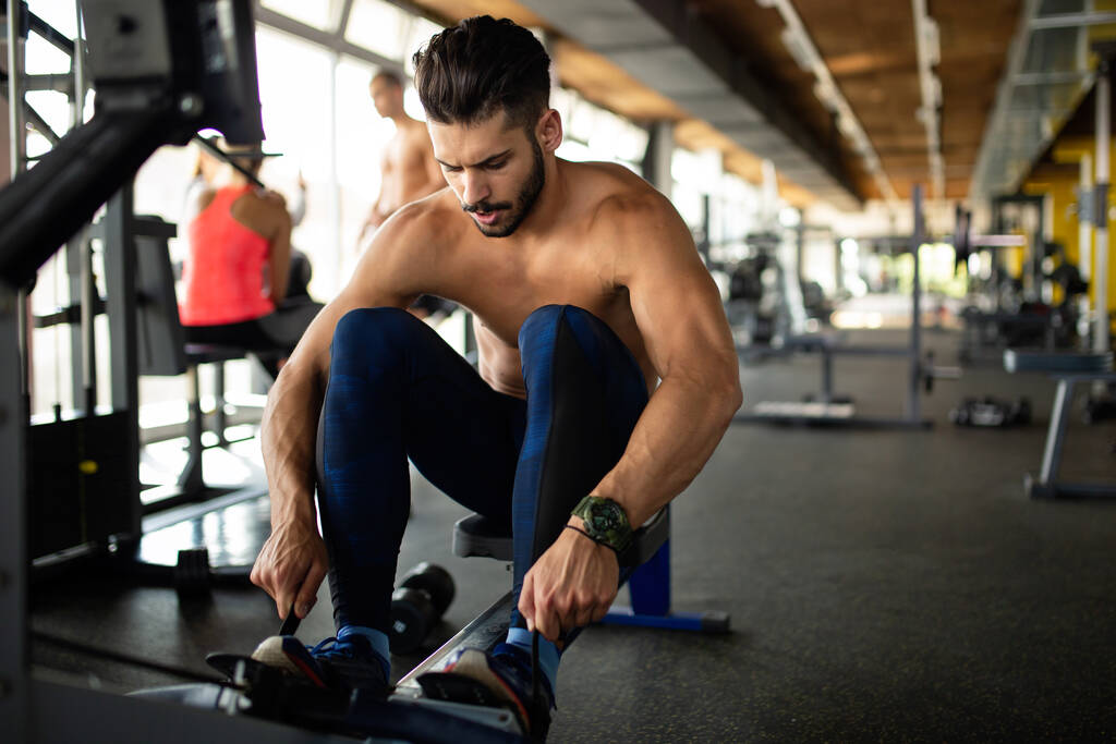 Young fit handsome man exercising in a gym to stay healthy. Sport people workout concept - Photo, Image