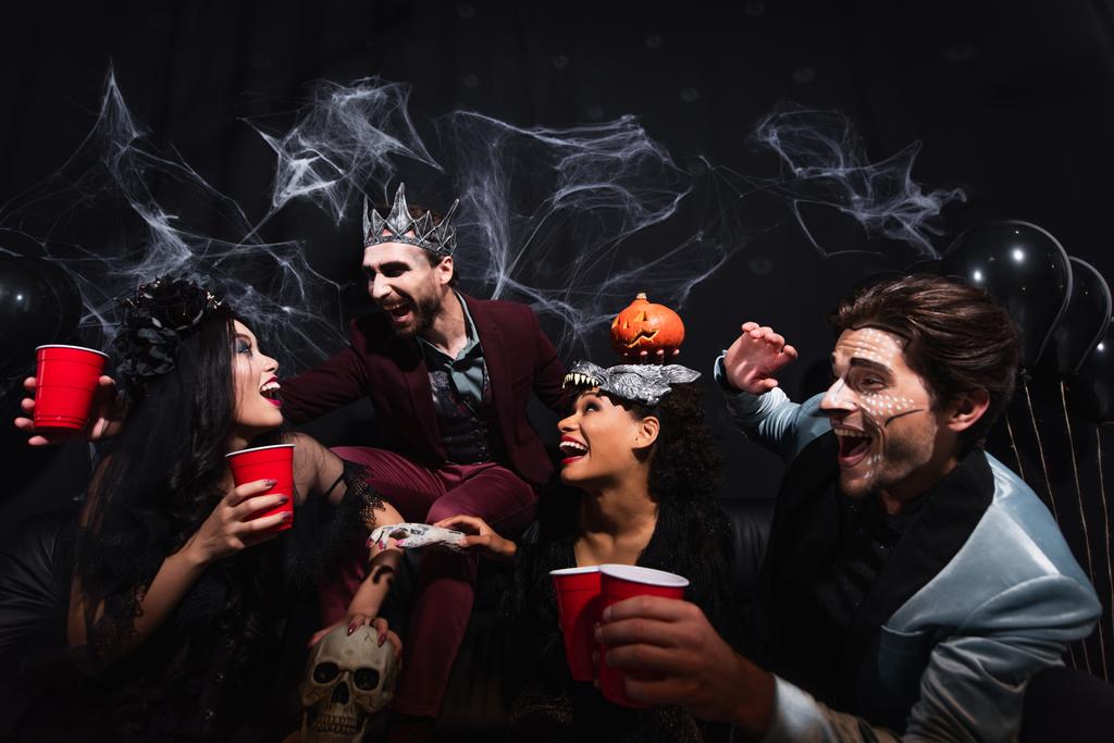 innoissaan monikansallisia ystäviä muovi kupit nauraa aikana halloween puolue musta   - Valokuva, kuva