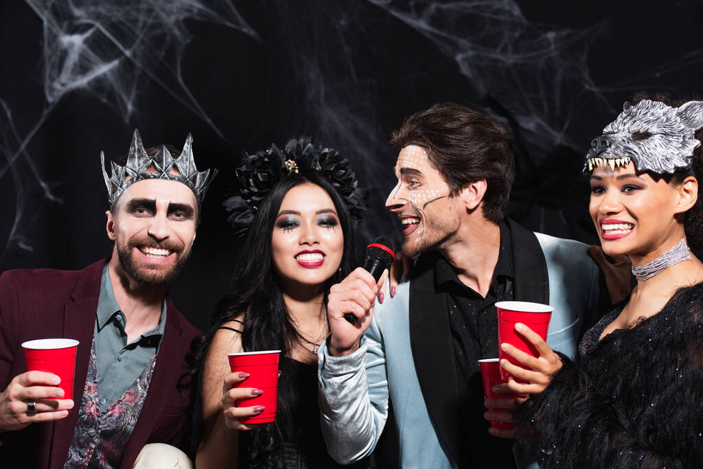 mies halloween meikki laulaa karaokea lähellä monikansallisia ystäviä muovi kupit musta - Valokuva, kuva