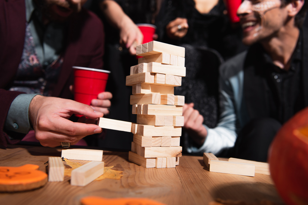 μερική άποψη του θολή φίλους παίζει ξύλο μπλοκ παιχνίδι κατά τη διάρκεια αποκριών κόμμα - Φωτογραφία, εικόνα