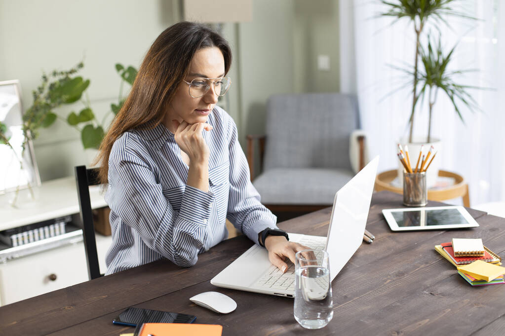 Una joven que trabaja con un portátil. Freelancer femenina conectándose a internet en casa. Blogger escribiendo nuevo artículo. - Foto, Imagen