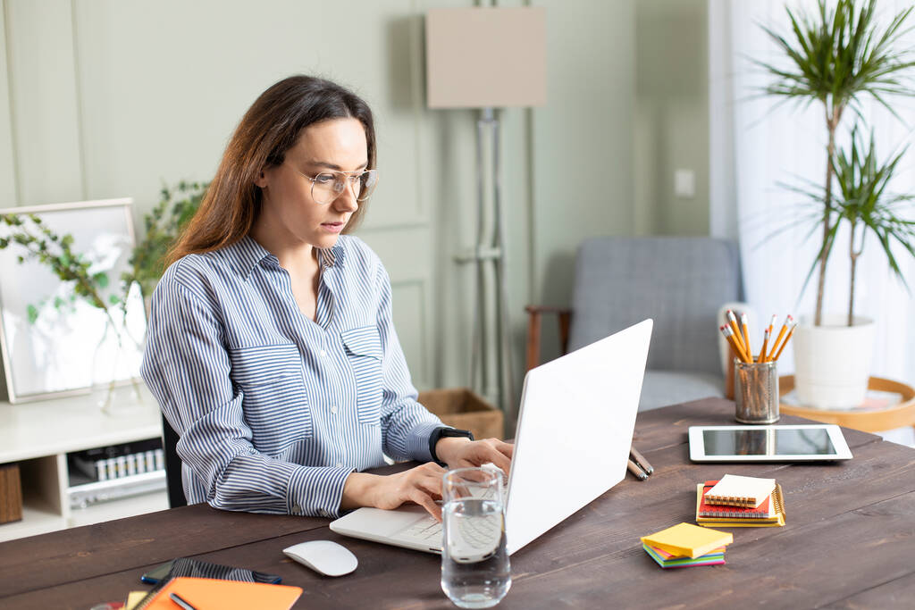 Una joven que trabaja con un portátil. Freelancer femenina conectándose a internet en casa. Blogger escribiendo nuevo artículo. - Foto, imagen
