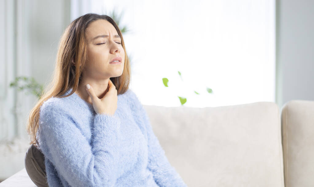 Junge Frau berührt schmerzenden Hals, Halsschmerzen wegen Grippe, Erkältung und Infektion - Foto, Bild